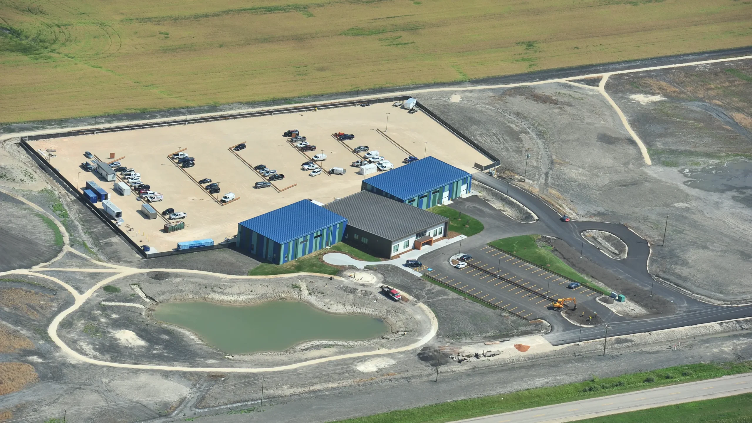 Aerial view of completed building and surrounding parking lots and pond