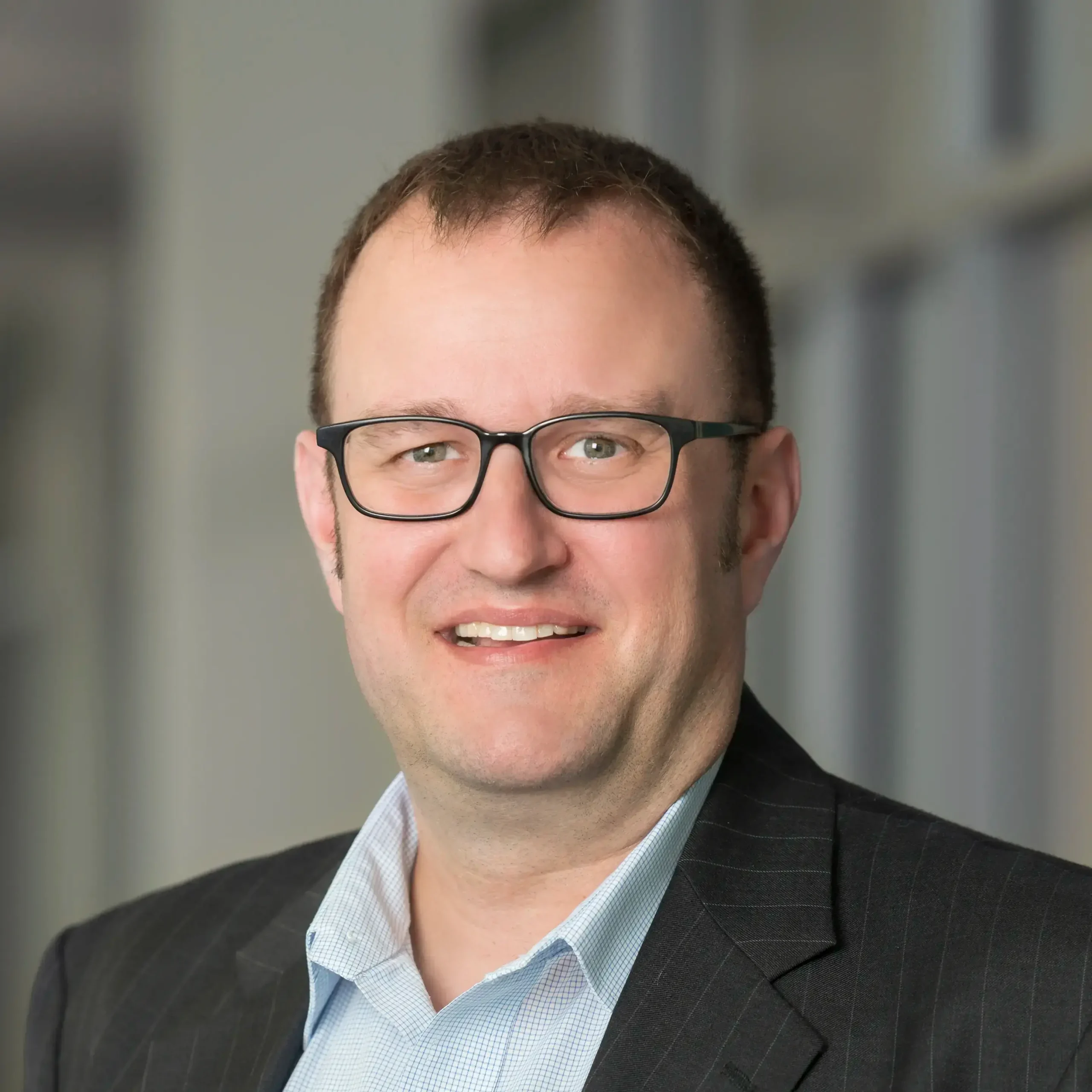 Adam Pawlikewich smiles confidently while standing in an office setting.