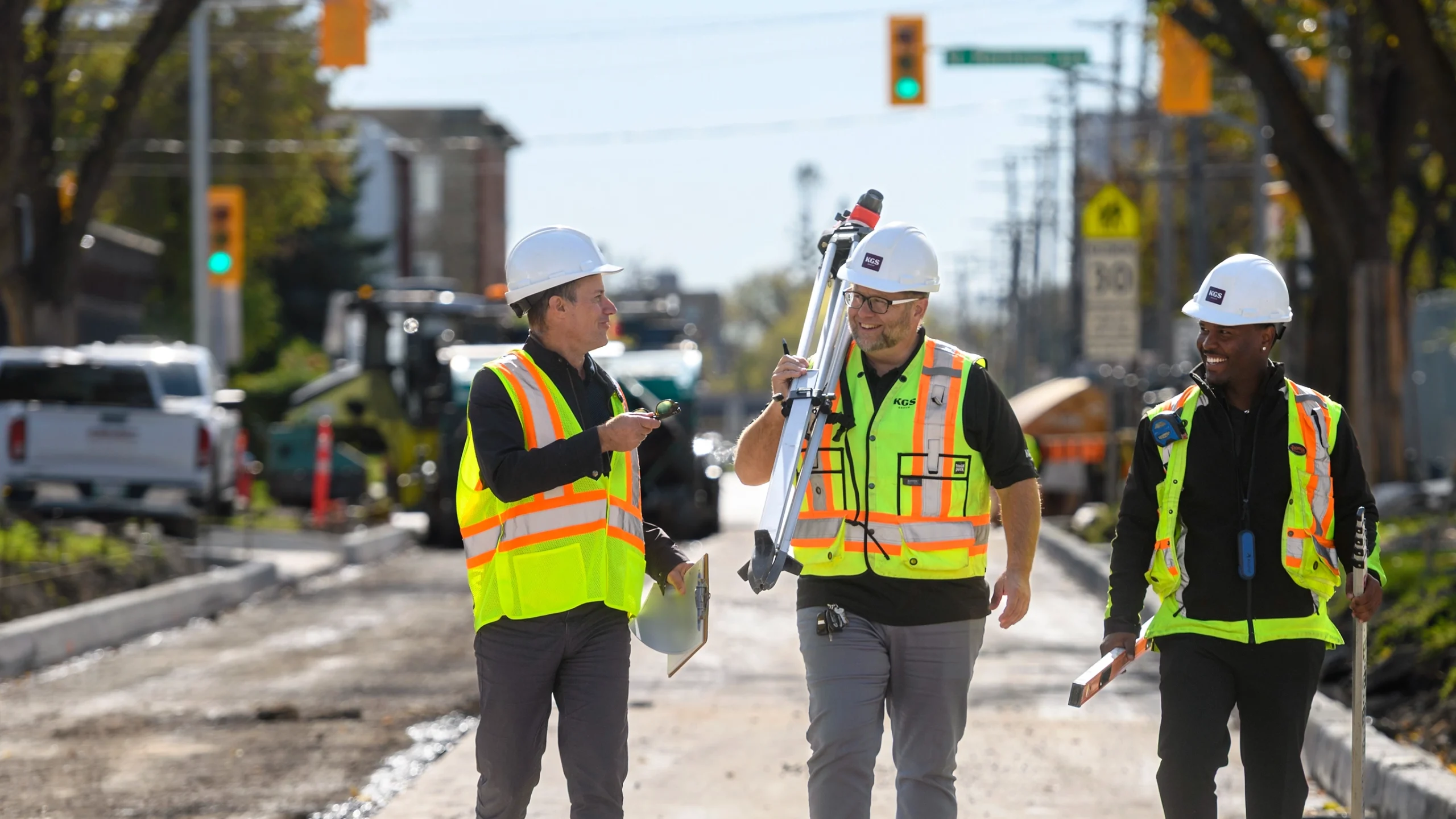 Three engineers walking down a road construction site
