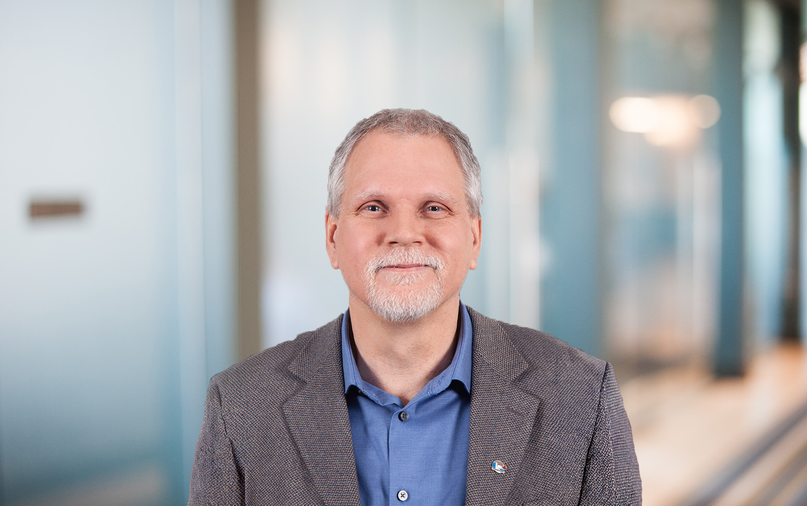 A man standing in front of an interior of an office space.