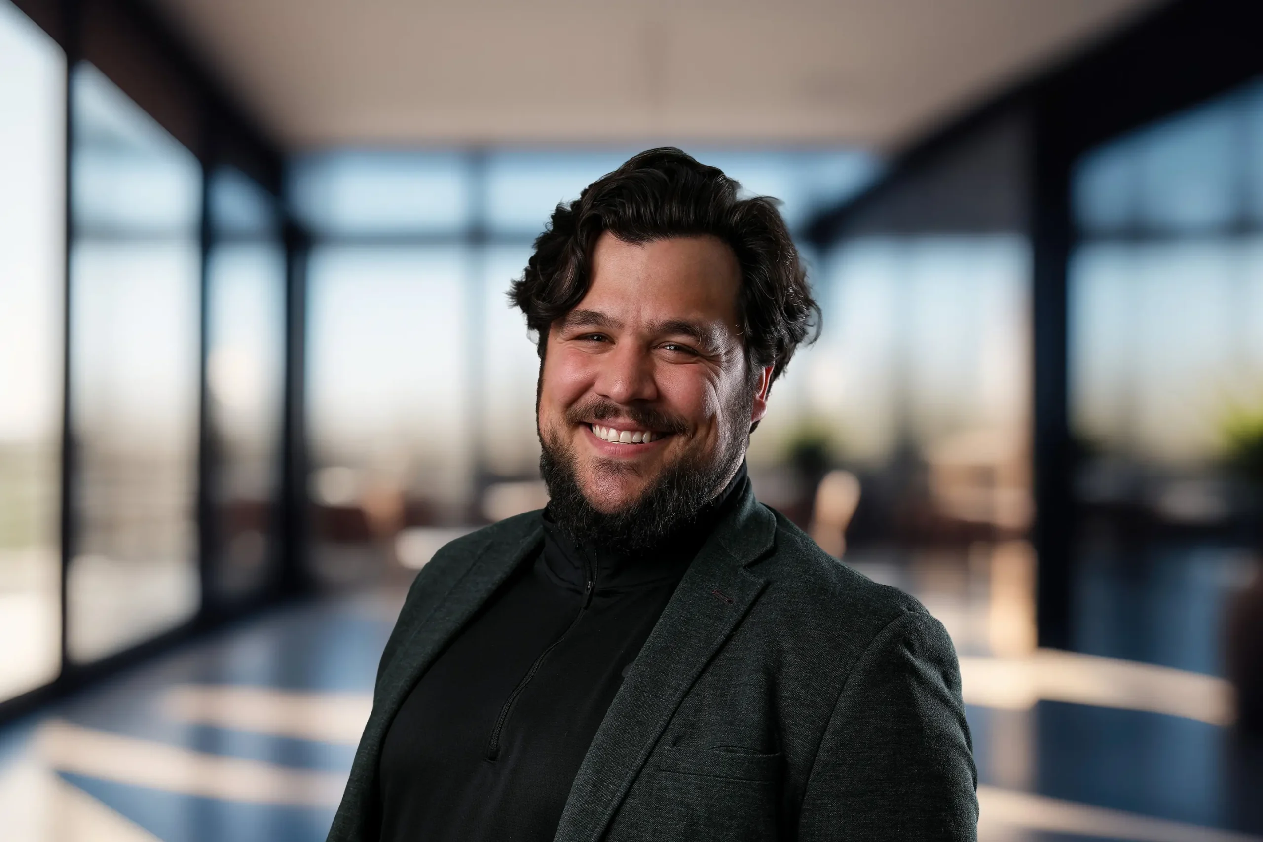 Aryian Farahani smiles confidently while standing in an office setting.