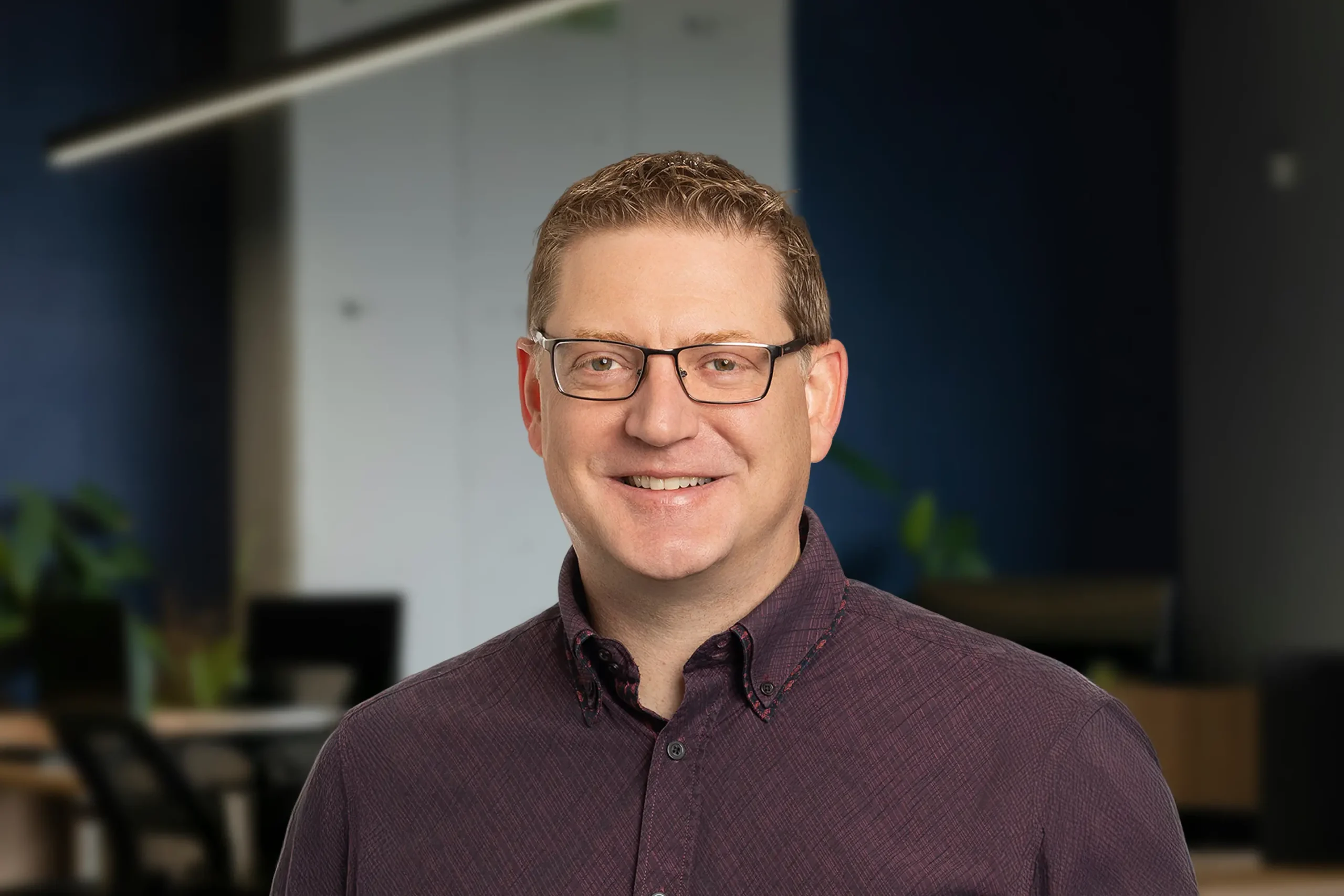 Ashton Richter smiles warmly while standing in an office setting.