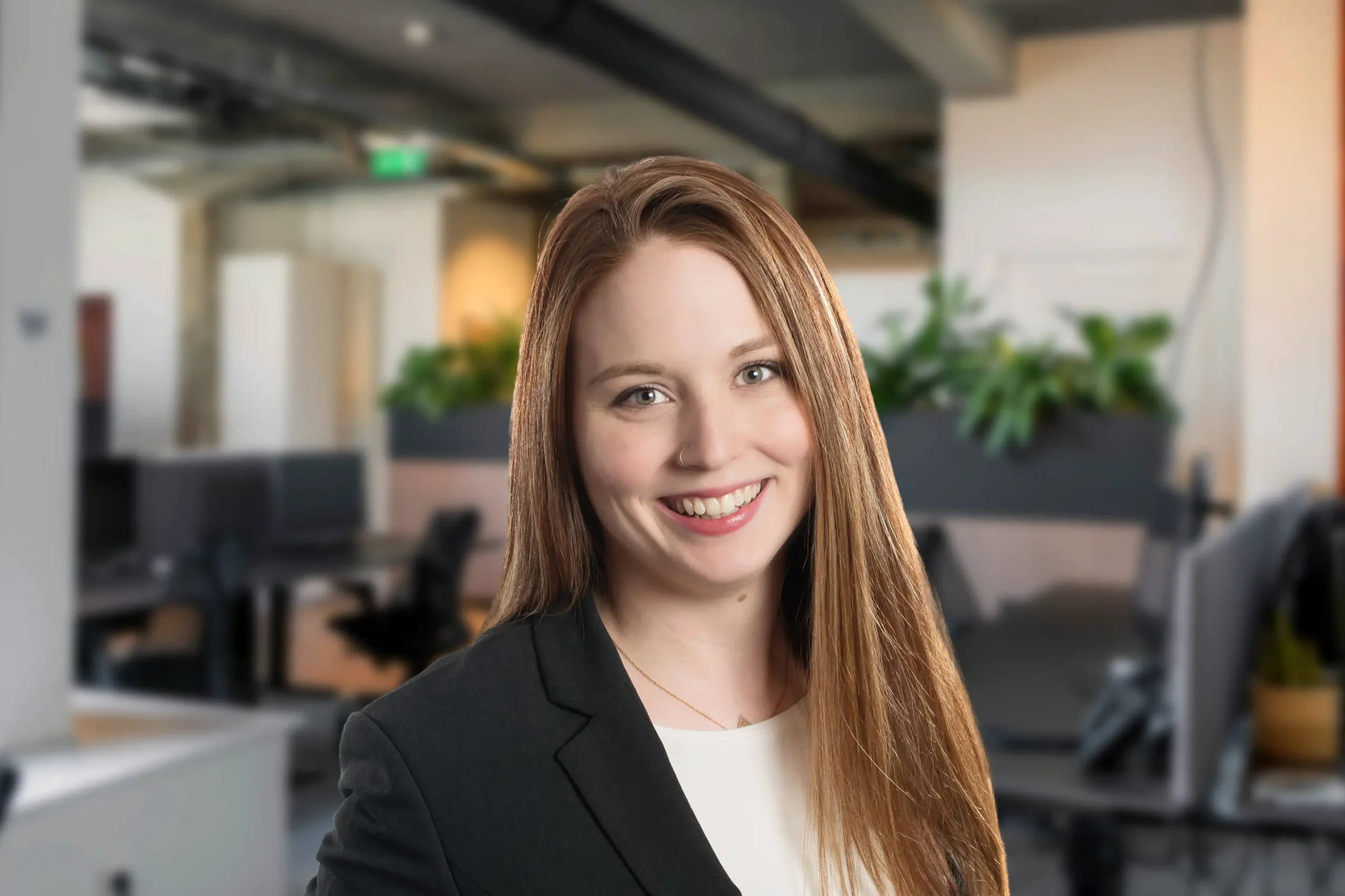 Destiny Piper smiles warmly while standing in a plant-filled office setting.