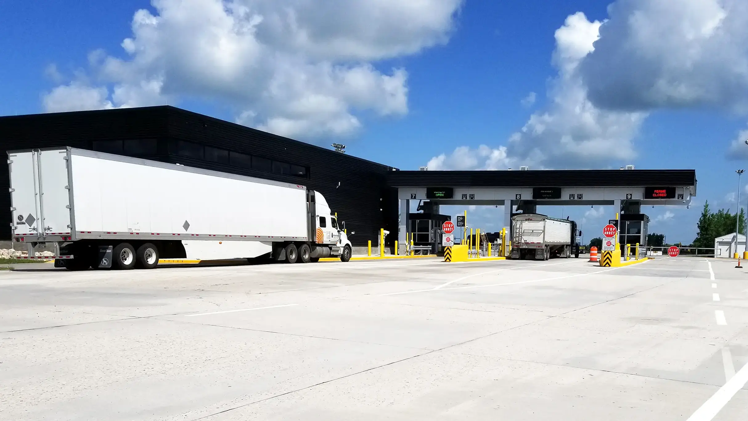 View of building with transport trucks entering inspection lanes