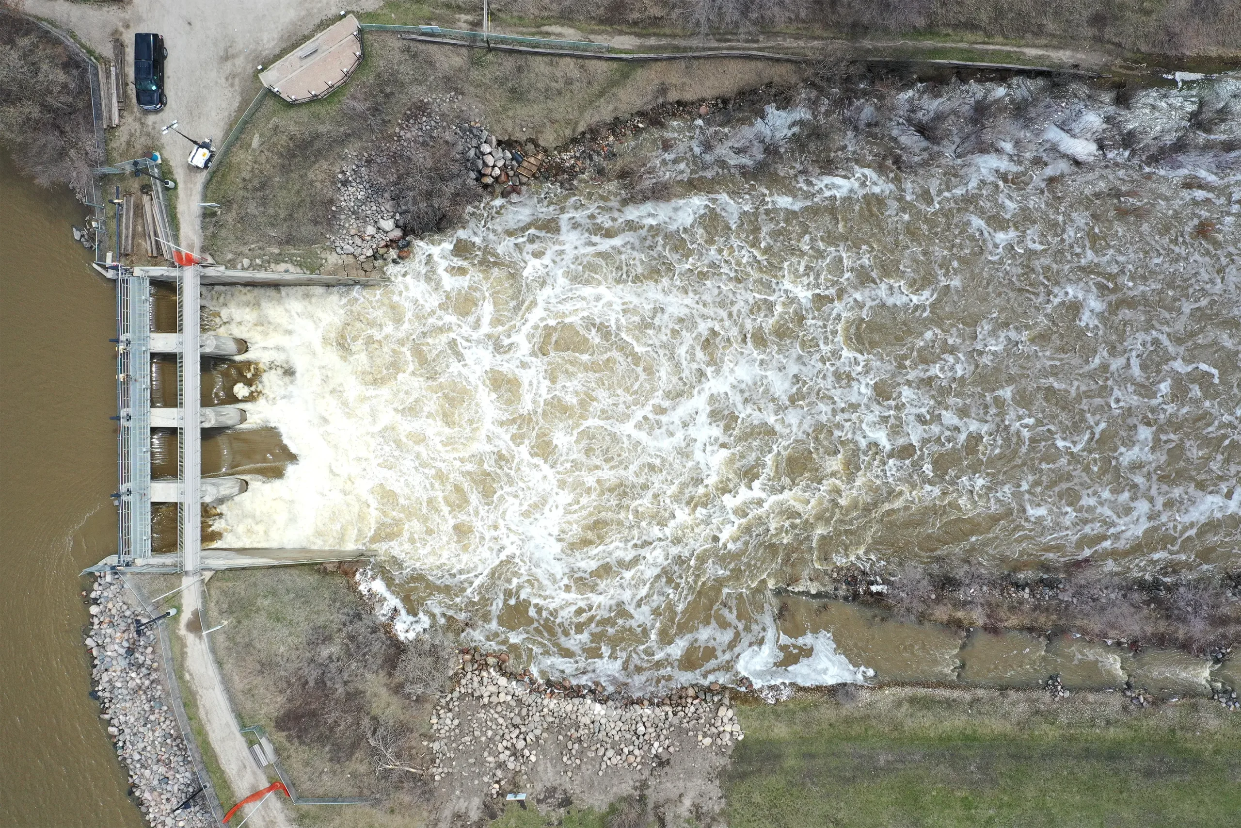 A bird’s‑eye view of a hydroelectric dam with water surging through its spillway.
