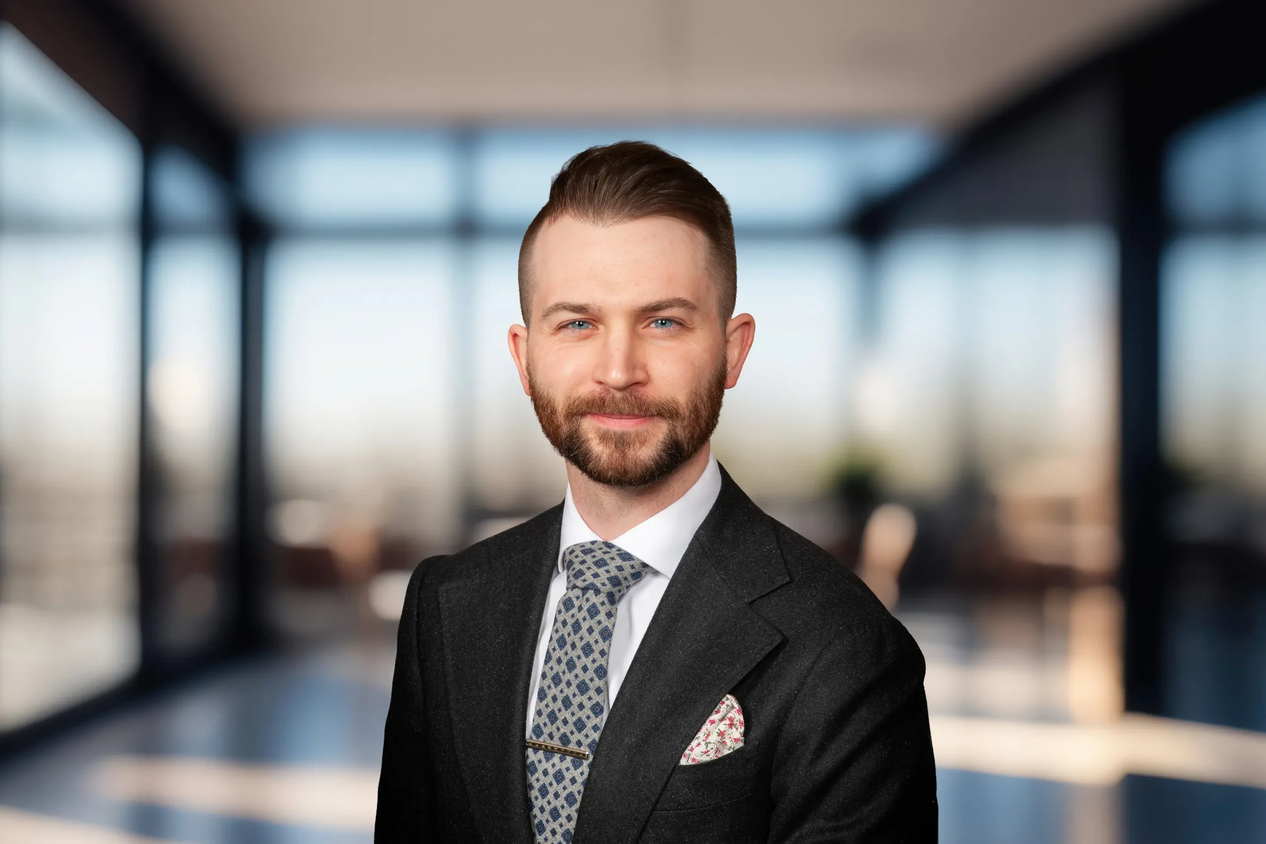 Nicholas Kaminski poses in a black suit, with a confident smile.