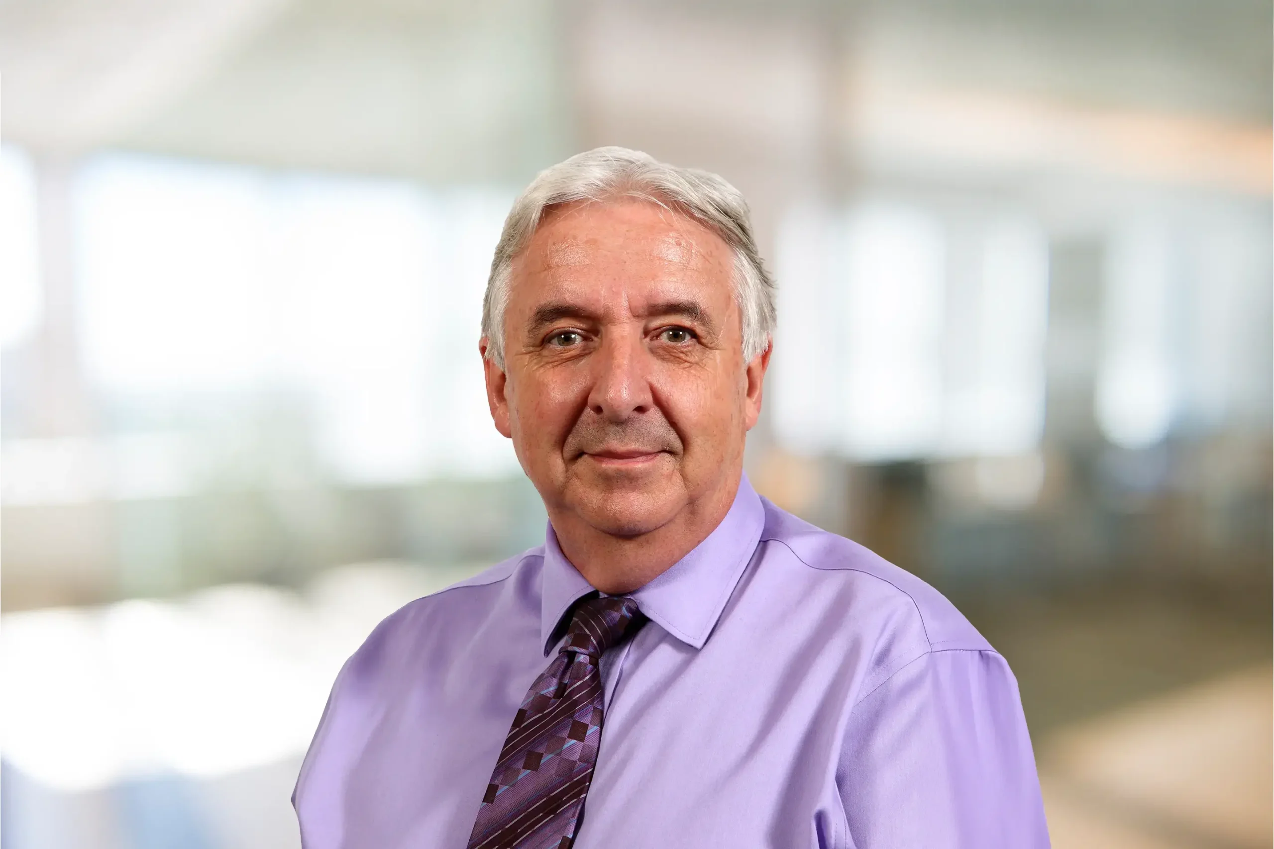 Rob Kenyon smiles warmly as he poses for a photo in a professional office environment.
