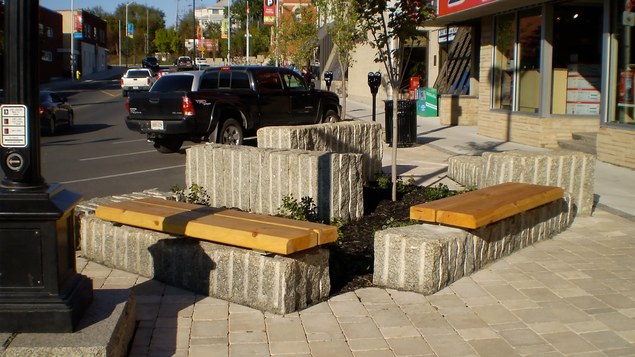 Two seating benches surrounded by planters in a downtown setting