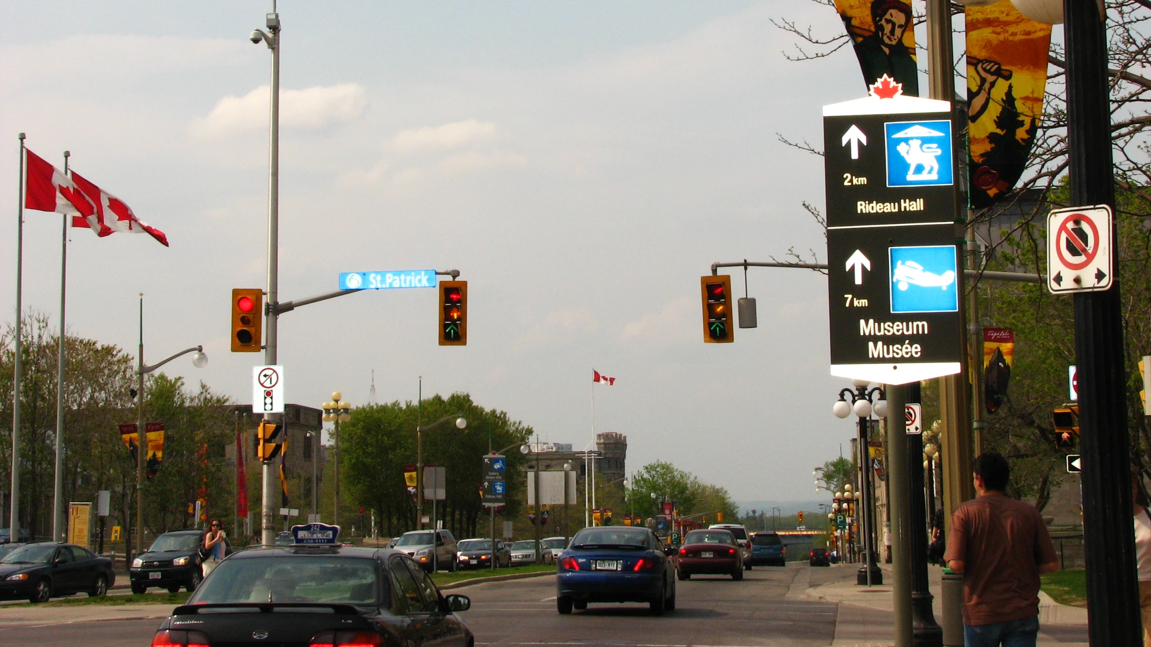 Busy downtown intersection with heavy traffic, red lights, and crowds of pedestrians crossing in multiple directions.