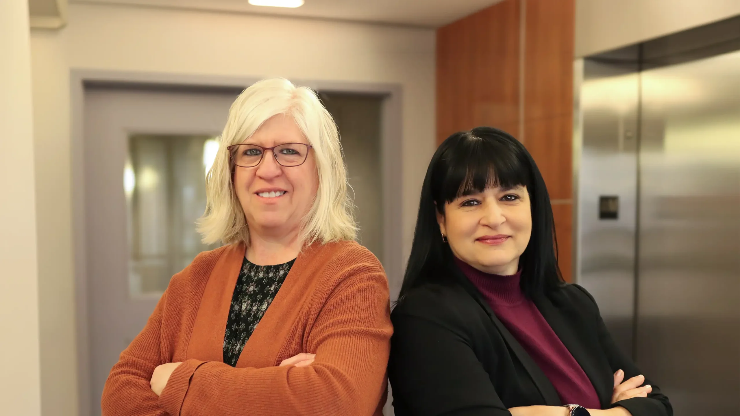 Women standing back to back in an office lobby